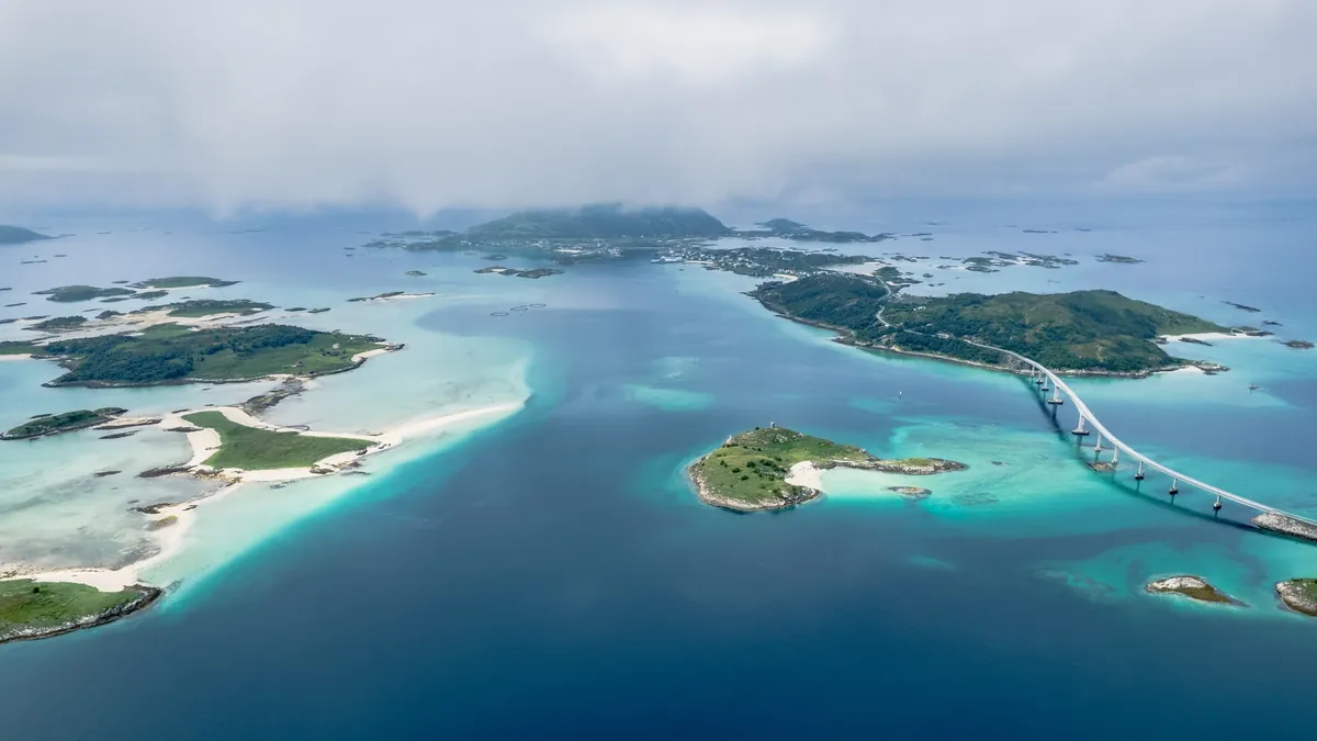 A bridge curving between small islands, turquoise shallows and deep blue water.
