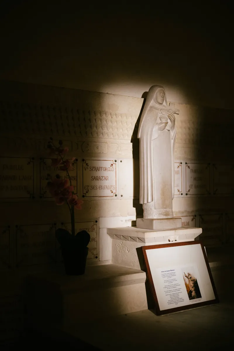 A religious statue lit in a narrow pool of warm light inside a dark church.